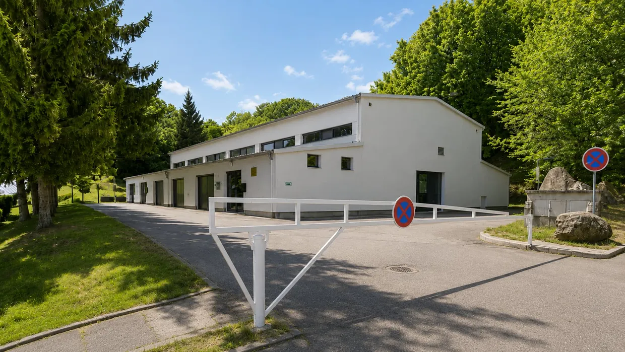 La salle communale Andrée-et-Marcel-Lefèvre vue de l'allée d'accès : bâtiment blanc au toit en pente, bandeau de fenêtres hautes, entouré de grands arbres.
